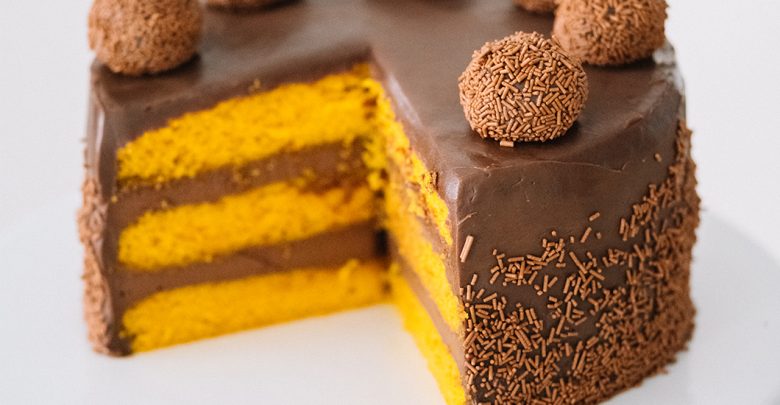Imagem de bolo de cenoura com brigadeiros de chocolate.